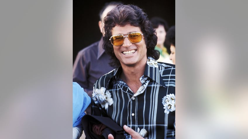 A close-up of Michael Landon smiling in a printed shirt and yellow sunglasses