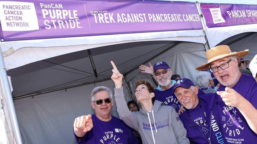 A group of people posing under a sign for PanCan