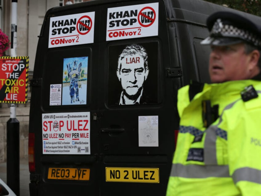 LONDON, UNITED KINGDOM - 2023/07/22: A police officer watches vehicles arriving with protest signs attached to their back doors outside the BBC. Protesters joined together to make it clear to London Mayor Sadiq Khan that he and the extension to the existing Ultra Low Emissions Zone (ULEZ) in London are …