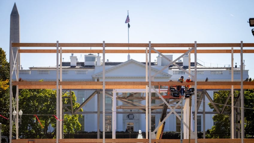 The Washington Monument and the White House are visible as workers assemble a media riser and the presidential inauguration parade review stand along Pennsylvania Avenue on Oct. 25, 2024.