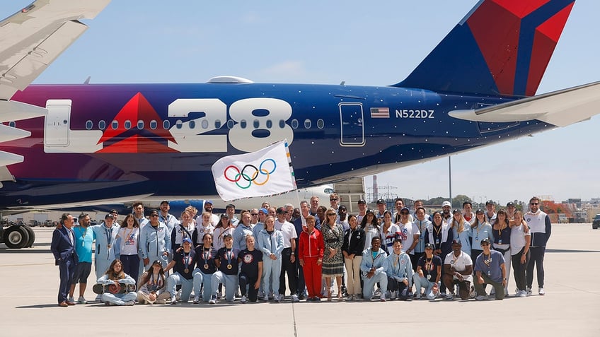 Karen Bass waves flag with contingent around plane