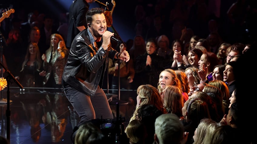 Luke Bryan bends his knees as he sings to the crowd in Nashville