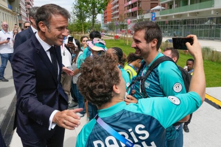 Emmanuel Macron poses for a selfie as the French president meets volunteers at the Athlete