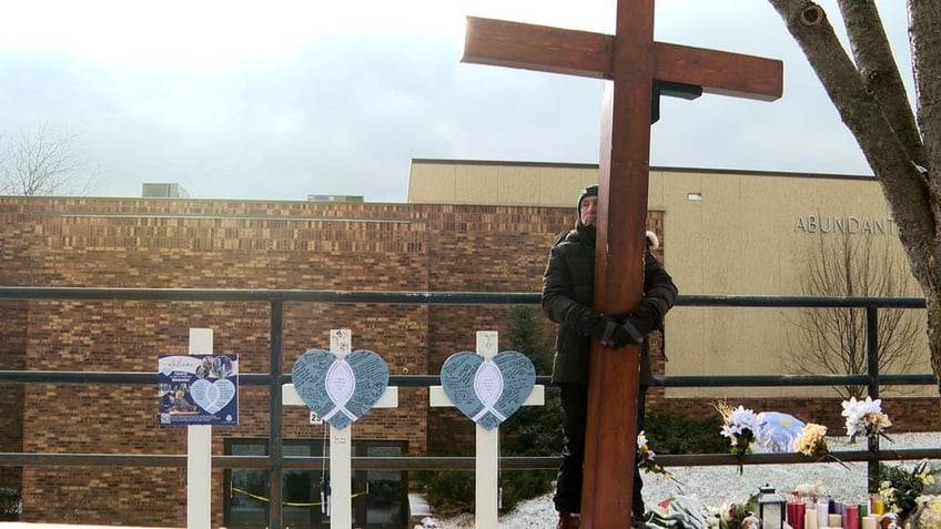 Man standing with cross after school shooting in Wisconsin