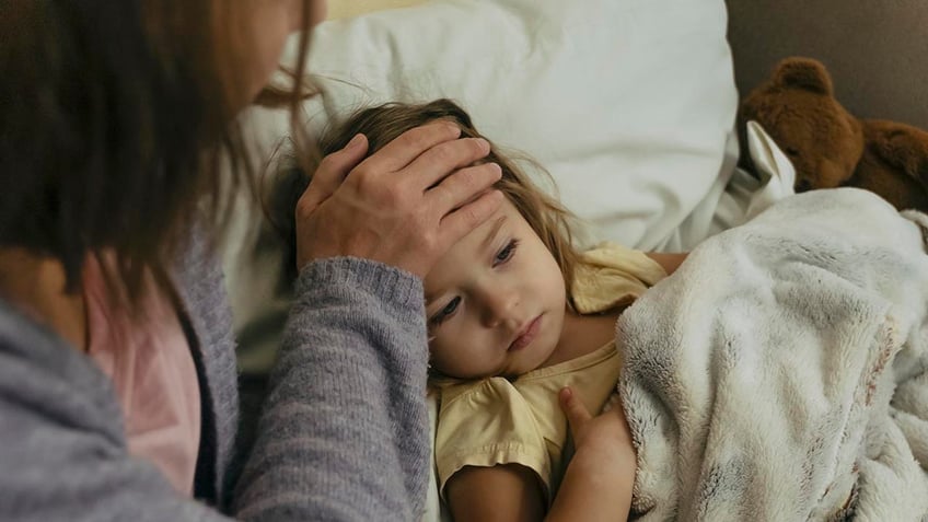 Sick child and mother touching child's forehead.