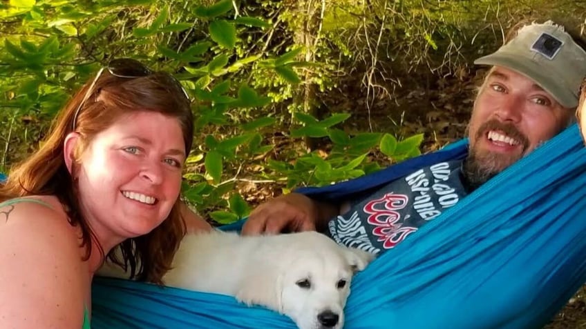 ginna and matt dix lying in a hammock with their dog