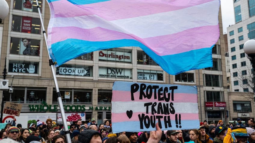 Demonstrator waves a trans pride flag during the Rise Up for Trans Youth rally