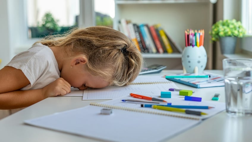 Kid with their head on a desk