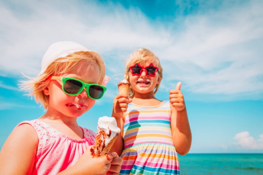 happy cute little girls eating ice cream on beach vacation