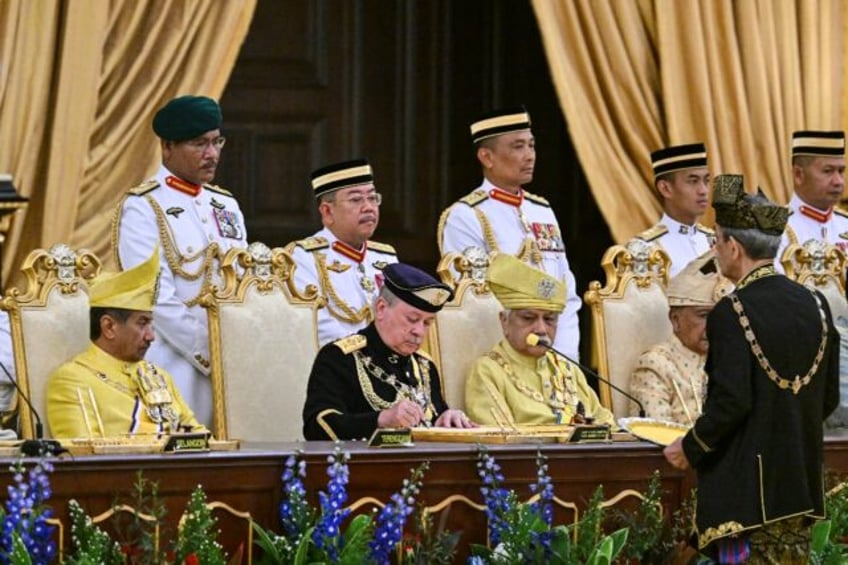 Sultan Ibrahim Iskandar (C) signs documents during his oath-taking ceremony Wednesday at Malaysia's National Palace