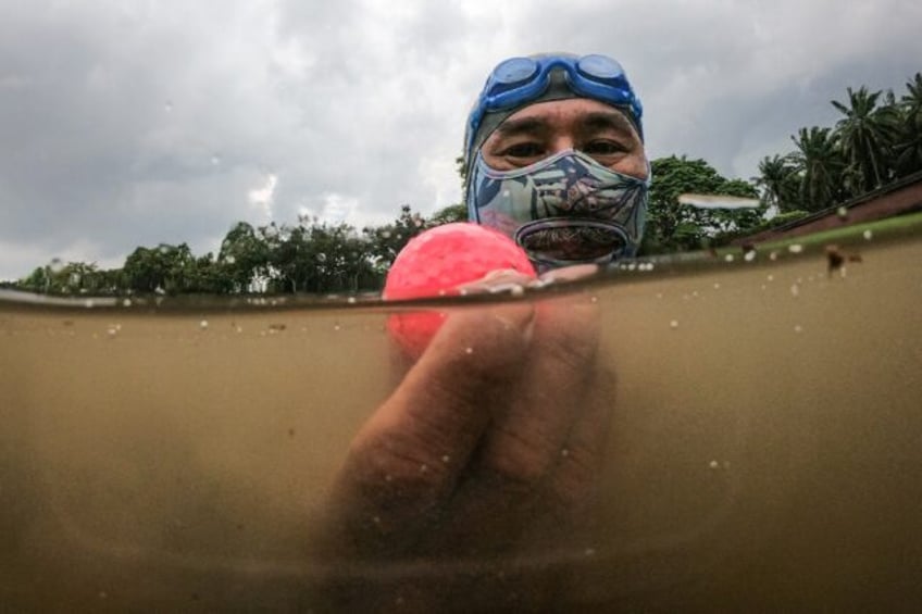 Retired navy frogman Sumadi Ibrahim, 51, with a golf ball he found in a pond at a course i