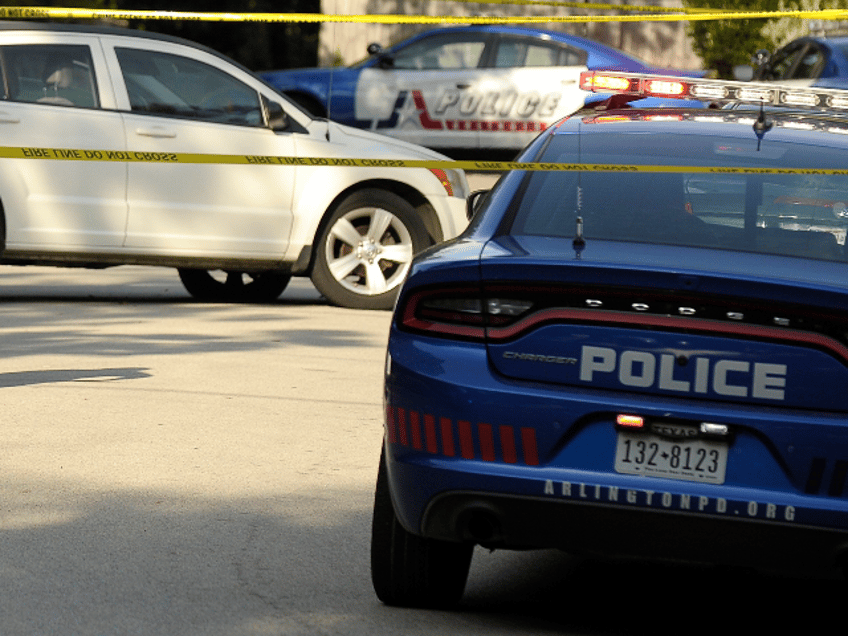 Arlington PD walking past the white Dodge sedan that a suspect car-jacked and abandoned ne