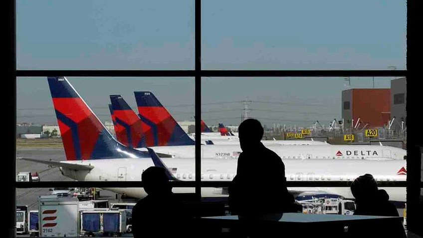 Travelers waiting for flights as Delta Air Lines planes 