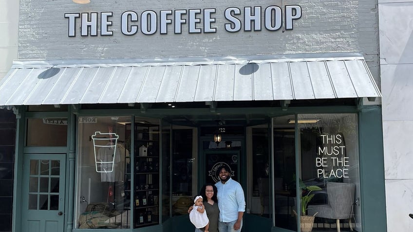 Man, woman, and child in front of The Coffee Shop, a cafe in Alabama.