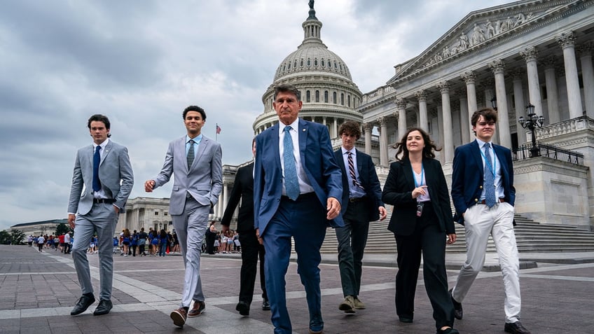 Manchin and staffers walk outside the Capitol