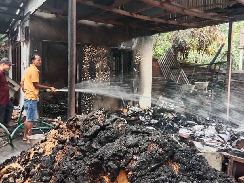 A worker sprays water to cool down burnt items at Union Minister of State for External Affairs R K Ranjan Singh's residence during ongoing ethnic violence in India's north-eastern Manipur state on June 16, 2023. (Photo by Anuwar Hazarika/NurPhoto)