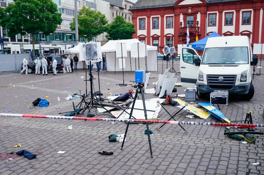 Forensics officers stand behind a smashed stall on the market square in Mannheim, Germany, Friday, May 31, 2024. An assailant with a knife attacked and wounded several people in a central square in the southwestern German city of Mannheim on Friday, police said. Police shot the attacker, who also was hurt. (Uwe Anspach/dpa via AP)