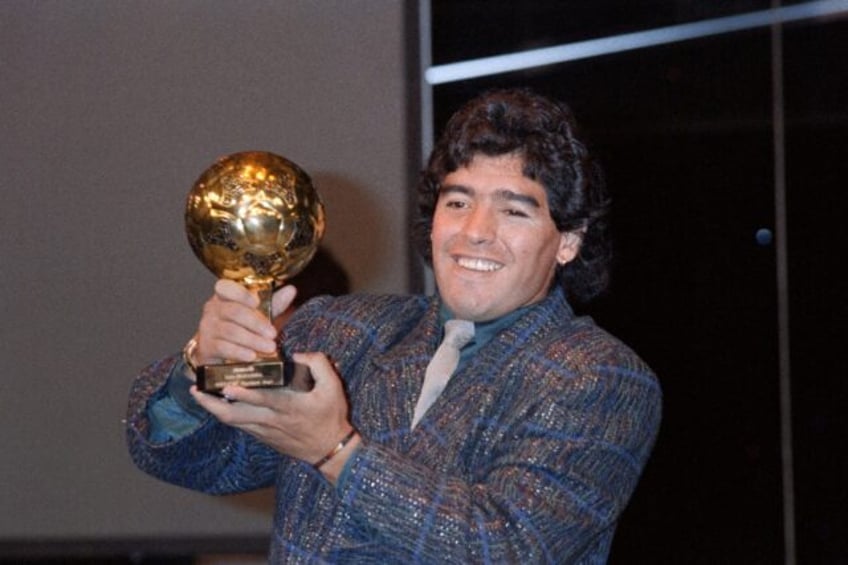 Diego Maradona poses with the 'Golden Ball' trophy at the Lido in Paris on November 13, 19