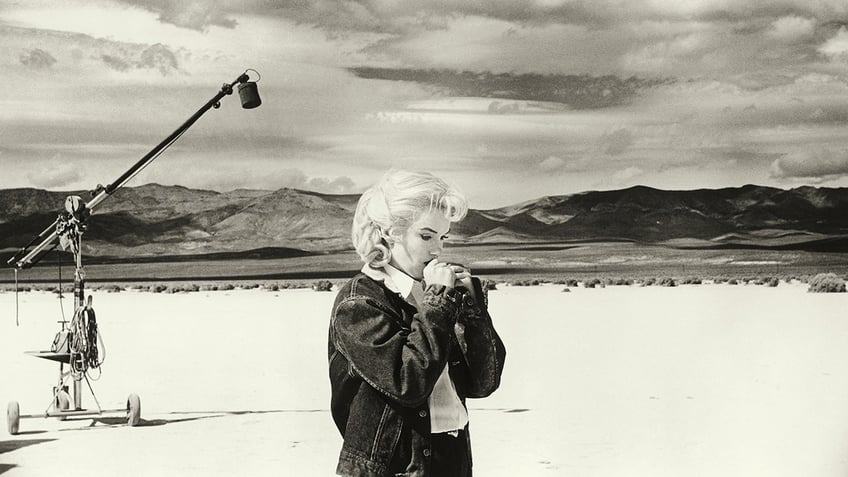 Marilyn Monroe looking somber in the desert with a boom mic behind her.