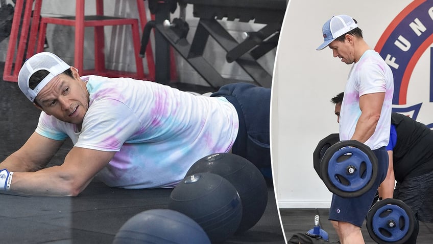 Mark Wahlberg on the floor of a gym with weighthed balls split lifting weights