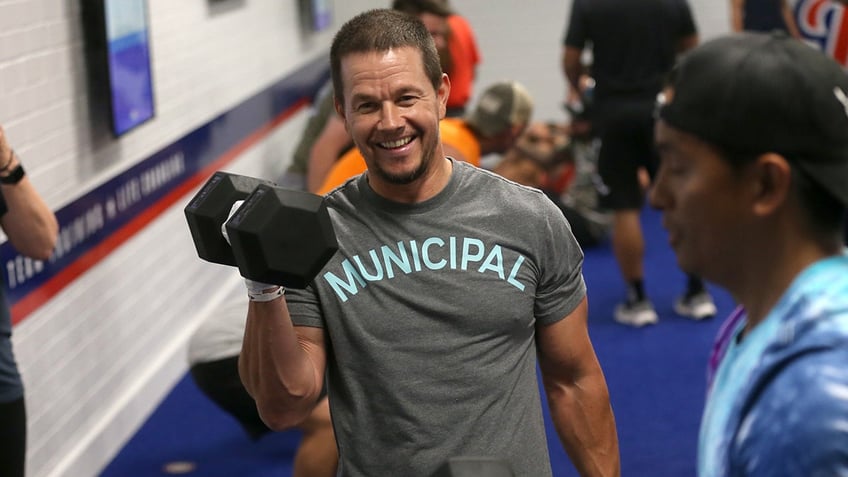 Mark Wahlberg lifting weights at the gym and smiling