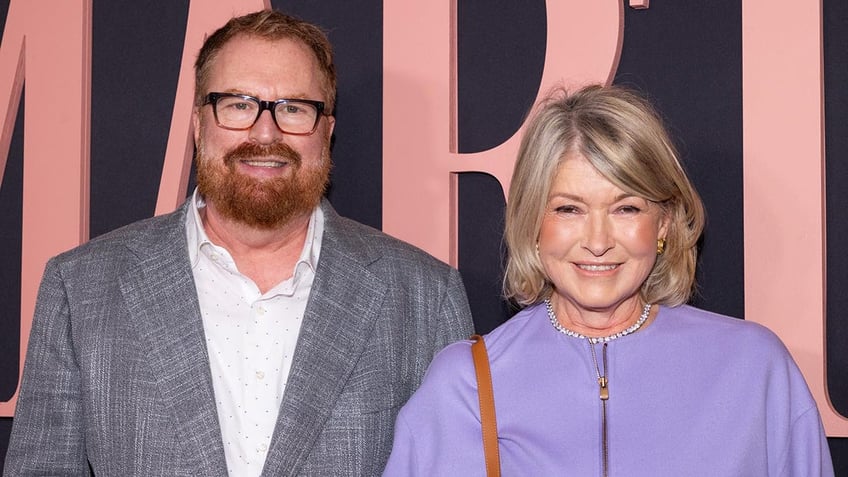 R.J. Cutler in a grey suit smiles at the premiere of "Martha" with Martha Stewart in a lavender jacket