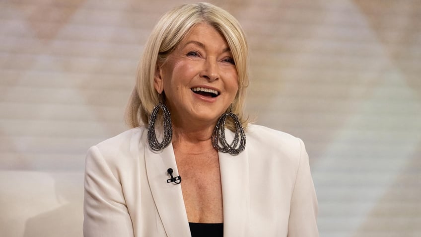 Martha Stewart laughing in a white blazer while looking up