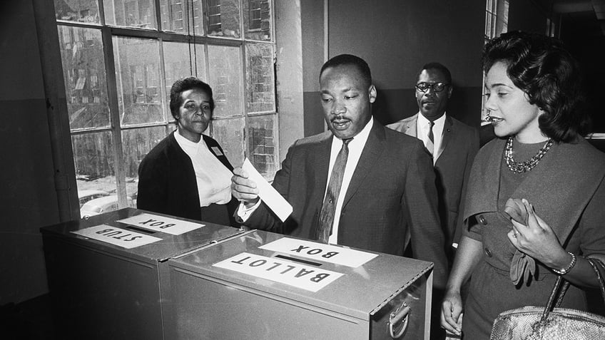 (Original Caption) 11/3/1964-Atlanta, GA: Dr Martin Luther King Jr votes as his wife, Coretta Scott King, waits her turn.