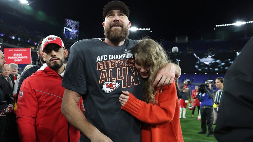 Taylor Swift and Travis Kelce hugging on the football field.