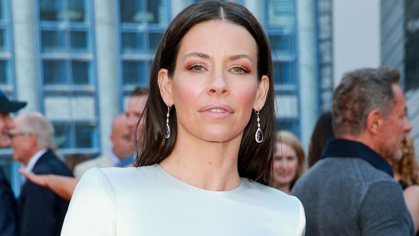 Actress Evangeline Lilly wears white dress on red carpet.