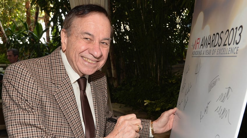 Richard M. Sherman smiling and signing a poster