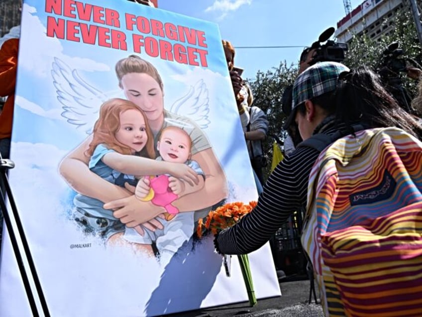 TEL AVIV, ISRAEL - FEBRUARY 26: A woman places flowers near a poster with members of the B