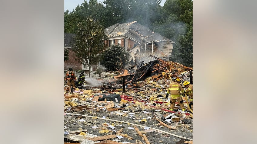 firefighters digging through debris of house explosion