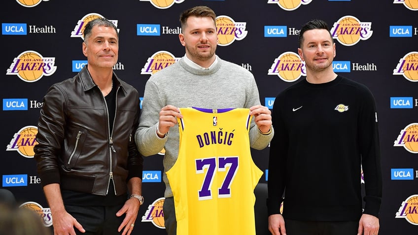 Luka Doncic holds up jersey