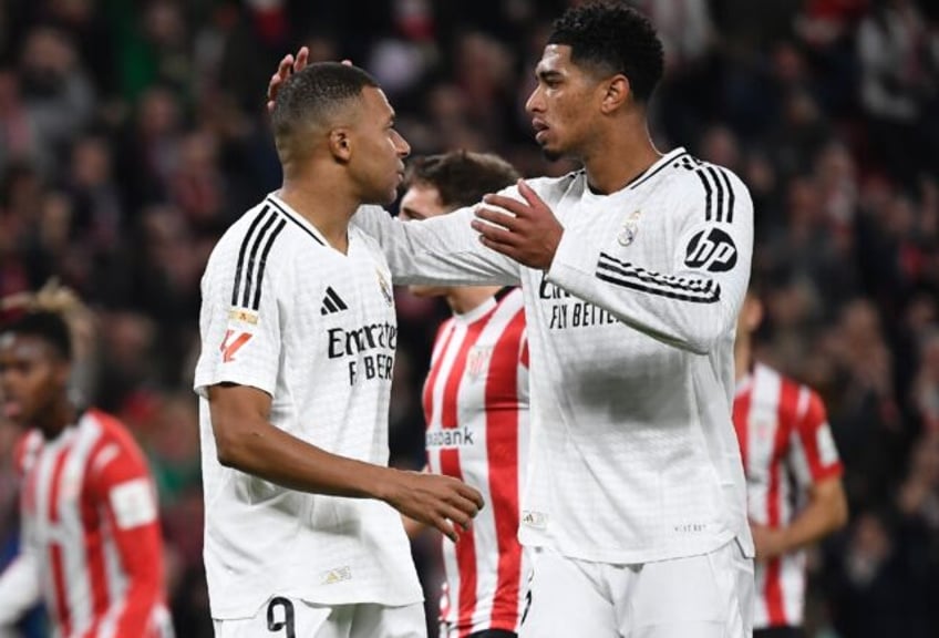 Real Madrid's French forward Kylian Mbappe (L) is comforted by Jude Bellingham after missi