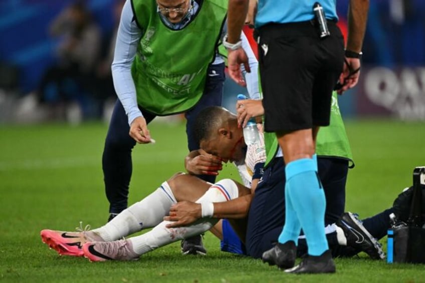 Kylian Mbappe receives medical treatment after breaking his nose during France's 1-0 win a