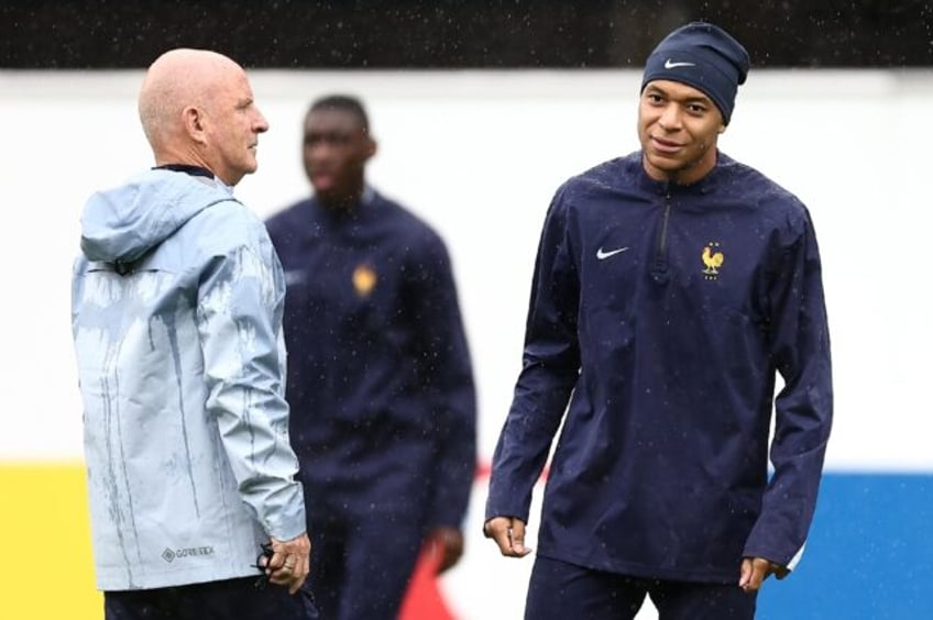 Kylian Mbappe (R) speaks with France assistant coach Guy Stephan at a training session on