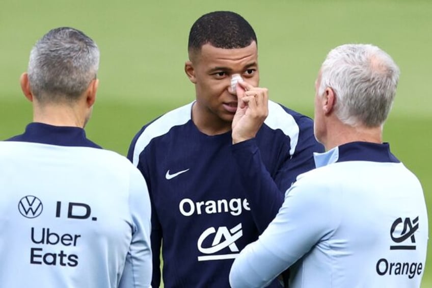 Kylian Mbappe, with a plaster on his broken nose, speaks to France coach Didier Deschamps