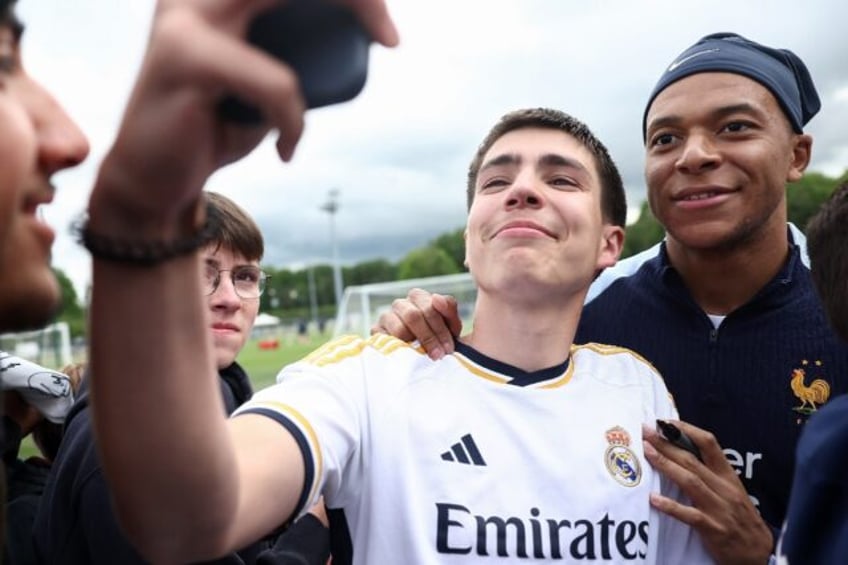 French forward Kylian Mbappe (R) poses for a photograph with a fan wearing a Real Madrid j