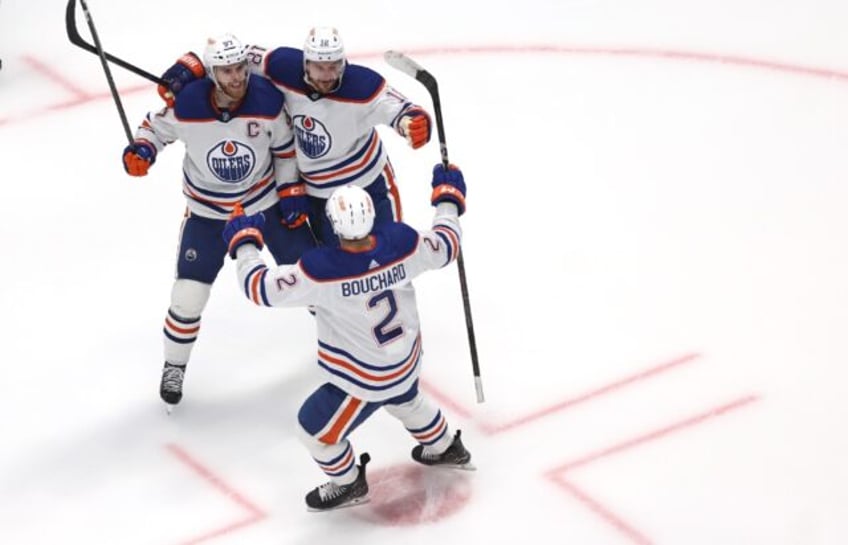 Connor McDavid, Zach Hyman and Evan Bouchard of the Edmonton Oilers celebrate McDavid's g