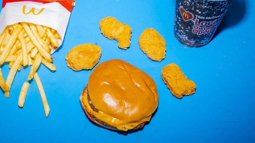 A cheeseburger with four nuggets on top of it arranged. The nuggets are each in the iconic shapes.