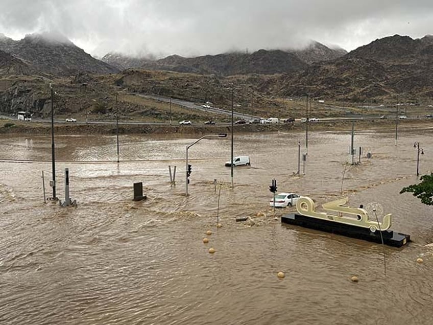 Commuters make their way through a flooded road after heavy rains in Mecca on January 6, 2