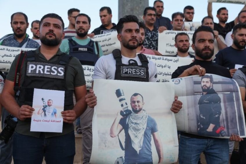 Syrian journalists lift placards protesting the detention of colleague Bakr al-Kassem