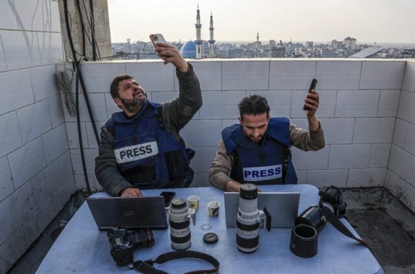 Palestinian journalists attempt to connect to the internet using their phones in Rafah on