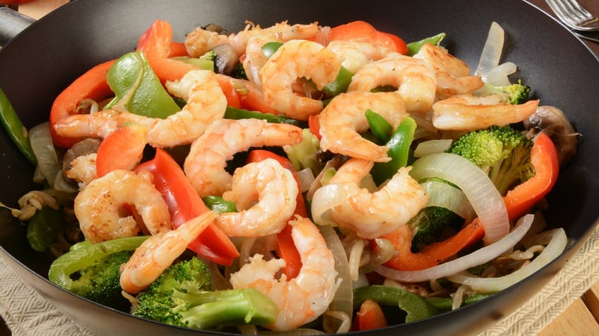 This is a picture of shrimp stir-fry and vegetables in a wok.