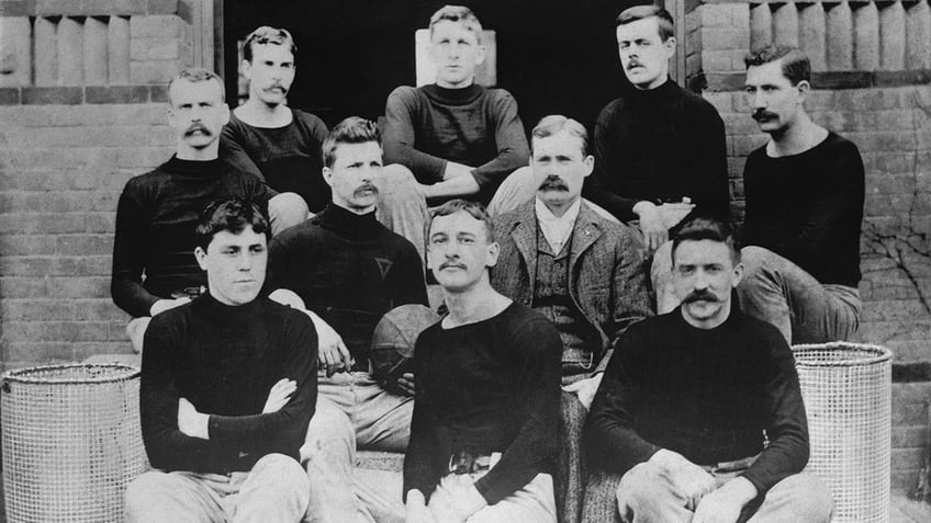 The first basketball team, consisting of nine players and their coach on the steps of the Springfield College Gymnasium in 1891 are shown. Dr. Naismith is in civilian clothes and grouped about him are left to right from back row: John G. Thompson, Eugene S. Libby, Edwin P. Ruggles, William R. Chase, and T. Duncan Patton. In the center row are Frank Mahan and Dr. James Naismith. In the front row is Finlay G. MacDonald, William H. Davis and Lyman W. Archibald.