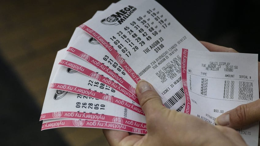 A person holds up their Mega Millions lottery tickets in New York City on August 08, 2023. If won, it would be the largest prize awarded in the lottery's history at 1.58 billion USD, with a 757.2 million USD cash option. (Photo by ANGELA WEISS/AFP via Getty Images)