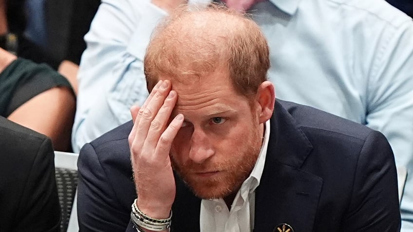 Prince Harry with his head down and touching his forehead at the Invictus Games