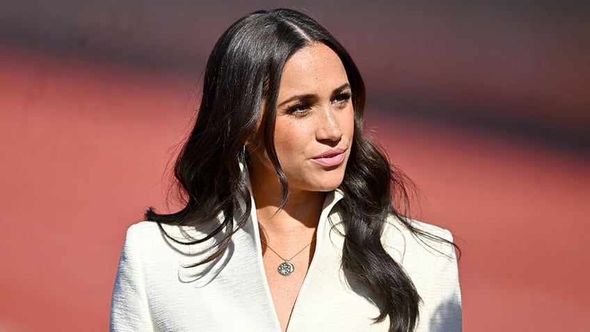 Meghan Markle looking to the side in an ivory blazer.