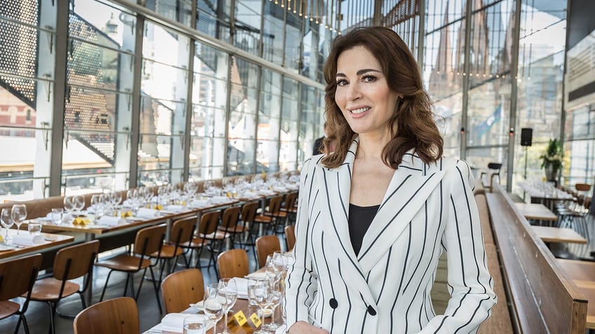 Nigella Lawson wearing a white and black striped blazer in front of a dining table.